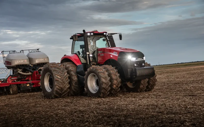 trator_magnum_em_campo_visto_lateralmente_a_direita_com_farois_acesos_em_aclive